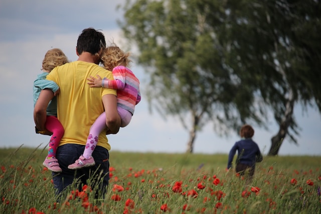 man carrying kids in field