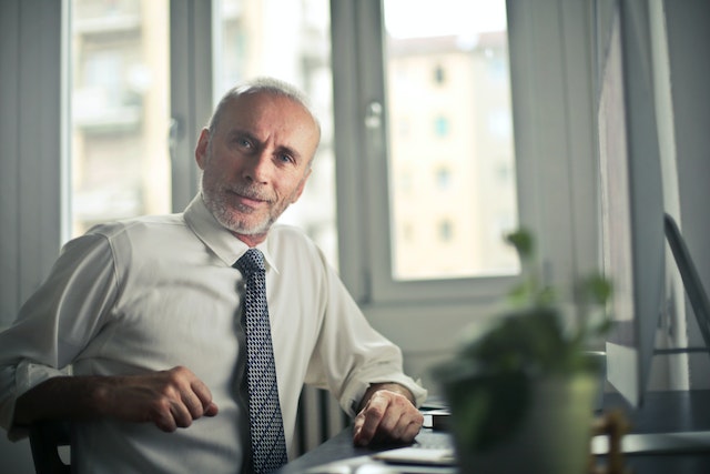 older man with tie at desk