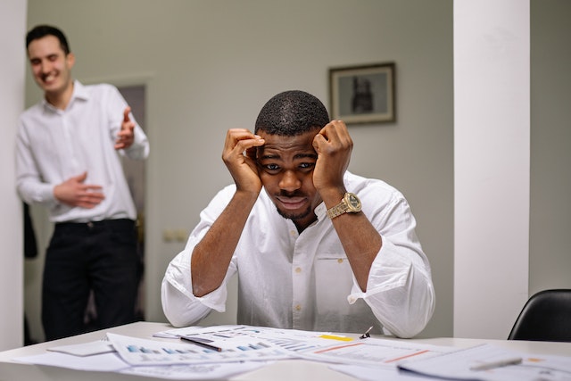 man laughing at sad coworker