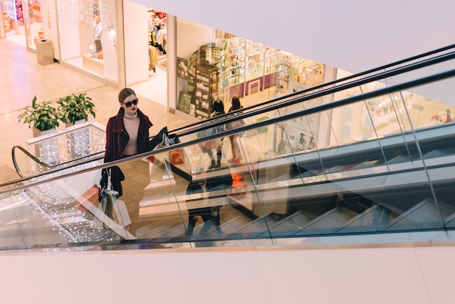 woman holding bag in mall on escalator