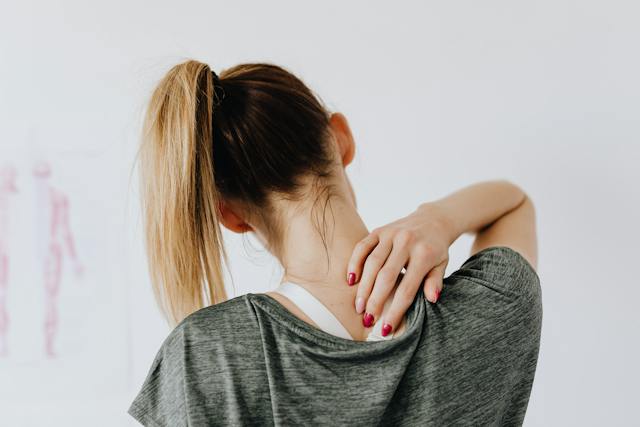 woman grabbing upper neck and spine in pain