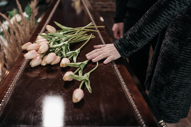 hand resting on a casket with flowers
